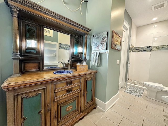 bathroom featuring toilet, vanity, and tiled shower