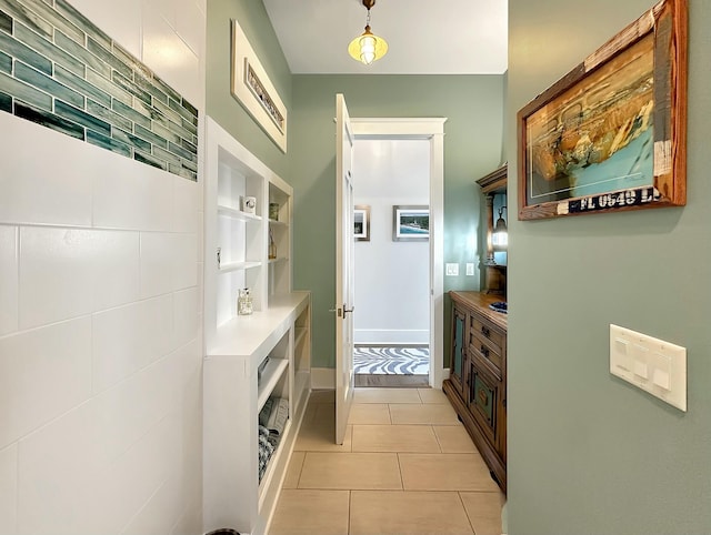 hallway with built in shelves and light tile patterned floors