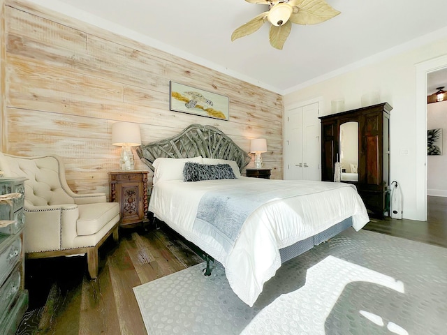 bedroom featuring dark hardwood / wood-style floors, ceiling fan, and wooden walls