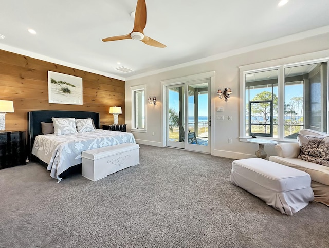 carpeted bedroom featuring access to exterior, ceiling fan, and wood walls