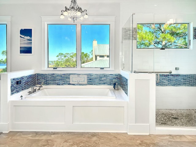 bathroom with shower with separate bathtub and an inviting chandelier