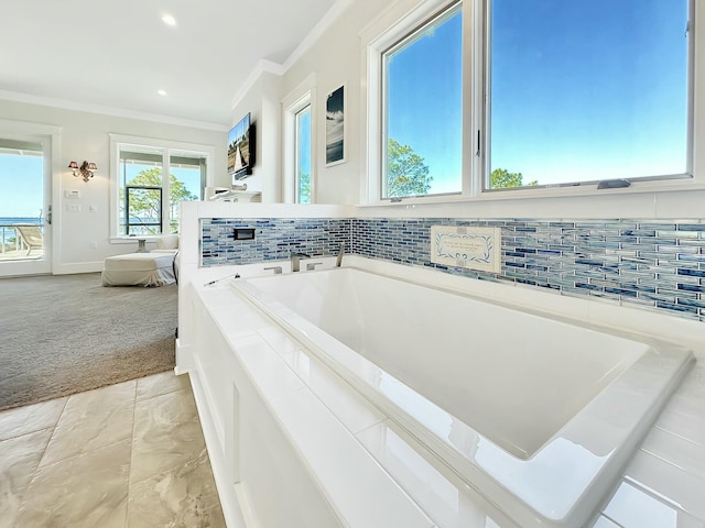 bathroom with a tub to relax in, ornamental molding, and backsplash