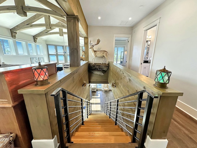 stairway with beamed ceiling and hardwood / wood-style flooring