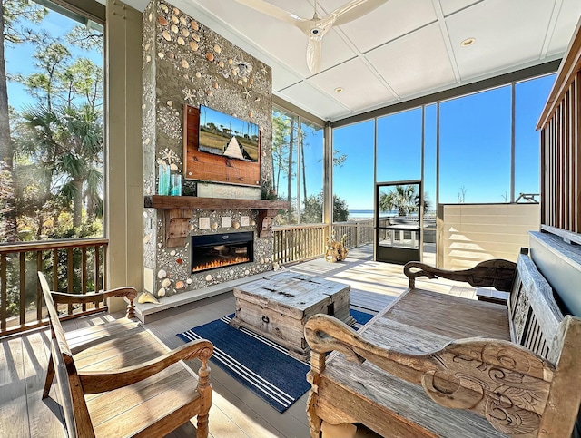 sunroom featuring ceiling fan and a tiled fireplace