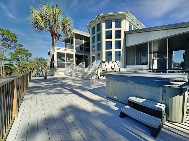 wooden deck featuring a hot tub and a sunroom