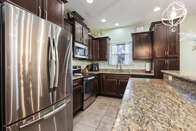 kitchen with light stone countertops, sink, hanging light fixtures, and appliances with stainless steel finishes