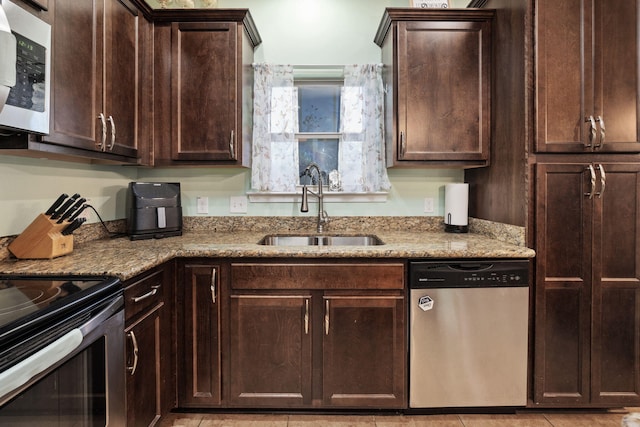 kitchen with light stone countertops, appliances with stainless steel finishes, dark brown cabinetry, sink, and light tile patterned floors