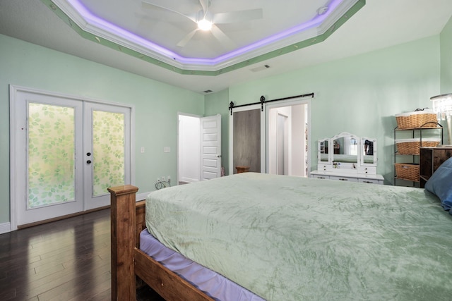 bedroom with a raised ceiling, a barn door, ceiling fan, and access to exterior