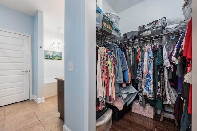 walk in closet with tile patterned flooring and a notable chandelier