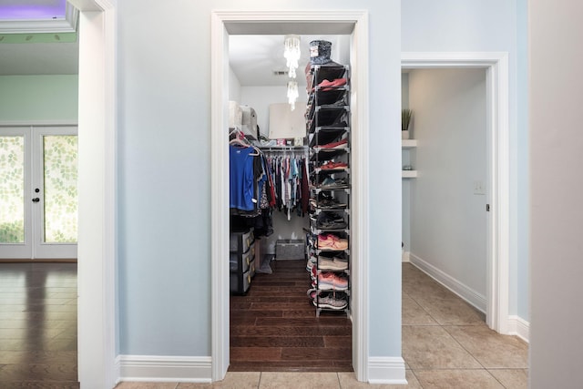 walk in closet with french doors and light hardwood / wood-style flooring