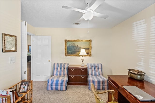 carpeted office space featuring ceiling fan and a textured ceiling