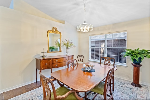 dining room with wood-type flooring, vaulted ceiling, and a notable chandelier