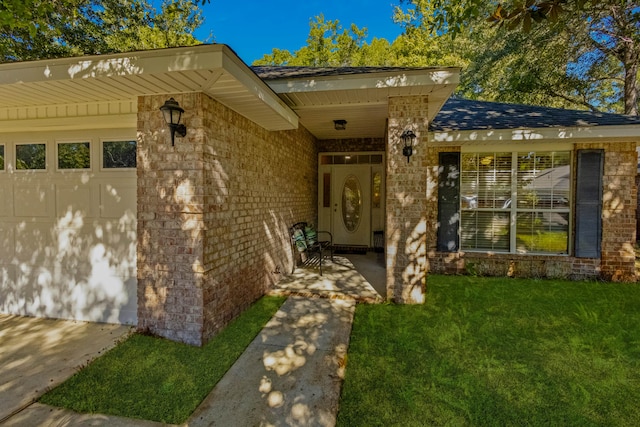 view of exterior entry with a lawn and a garage