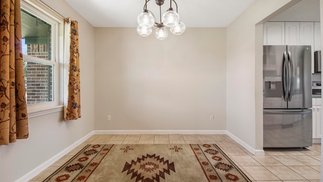 kitchen with an inviting chandelier, stainless steel fridge with ice dispenser, decorative light fixtures, light tile patterned flooring, and white cabinetry