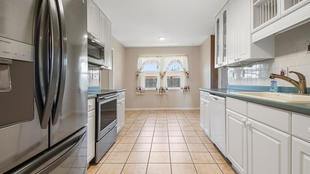 kitchen featuring white cabinets, sink, decorative backsplash, light tile patterned floors, and appliances with stainless steel finishes