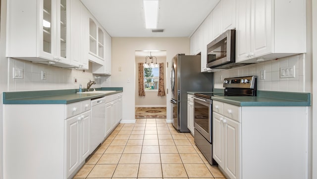 kitchen with decorative backsplash, appliances with stainless steel finishes, sink, light tile patterned floors, and white cabinets