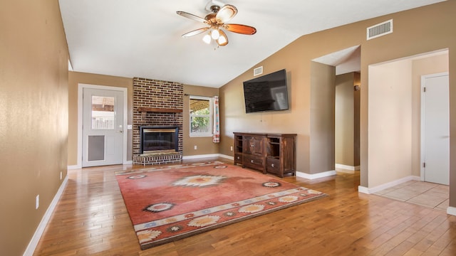 unfurnished living room featuring a fireplace, light wood-type flooring, ceiling fan, and lofted ceiling