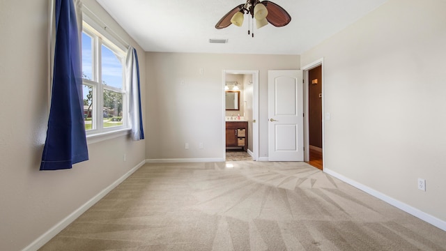 unfurnished bedroom with ensuite bathroom, ceiling fan, and light colored carpet