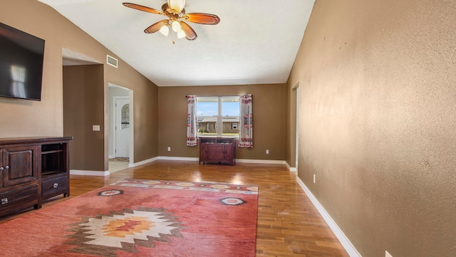 unfurnished living room with hardwood / wood-style flooring, vaulted ceiling, and ceiling fan