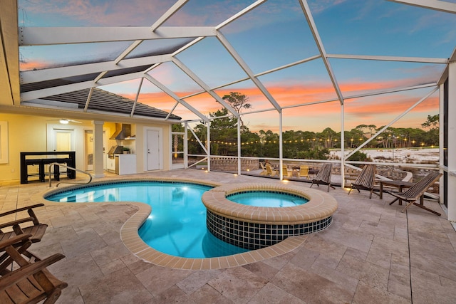 pool at dusk featuring a lanai, a patio area, and an in ground hot tub