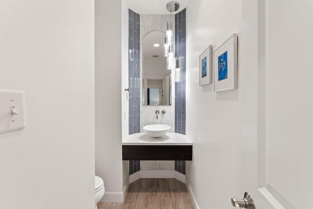 bathroom featuring wood-type flooring, vanity, a tile shower, and toilet