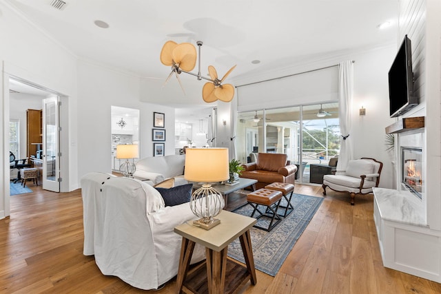 living room featuring light hardwood / wood-style flooring, a notable chandelier, and ornamental molding