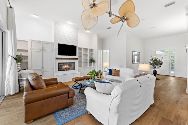 living room featuring light hardwood / wood-style floors, ceiling fan, and crown molding