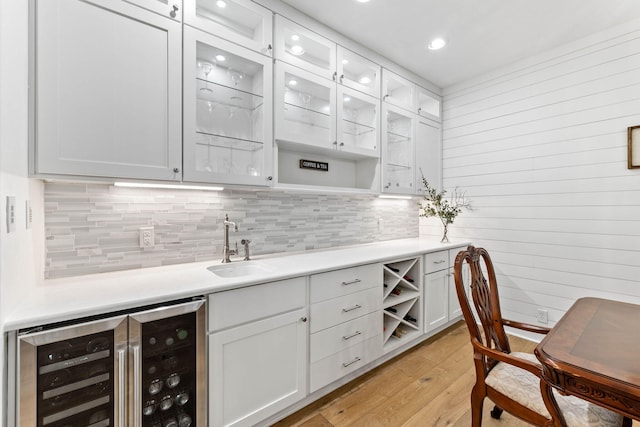 kitchen with light wood-type flooring, white cabinetry, wine cooler, and sink