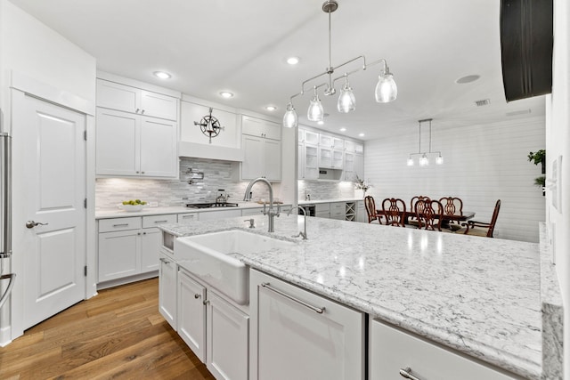 kitchen with tasteful backsplash, sink, decorative light fixtures, hardwood / wood-style floors, and white cabinetry