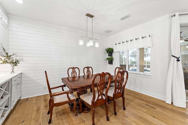 dining area with wooden walls and light wood-type flooring