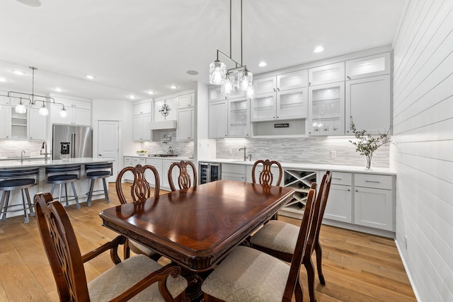 dining space featuring light hardwood / wood-style floors, beverage cooler, and sink