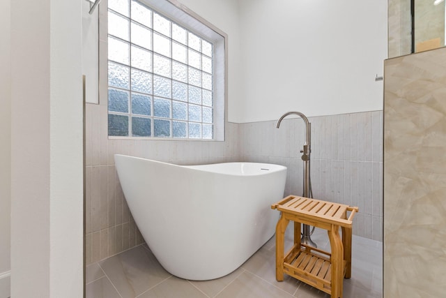 bathroom with tile patterned floors, a bathtub, and tile walls