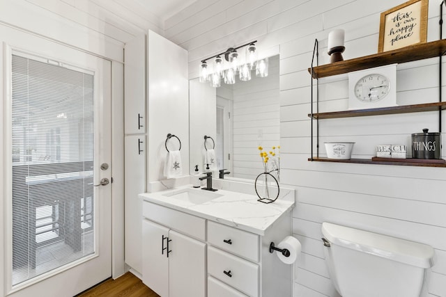 bathroom featuring vanity, hardwood / wood-style flooring, toilet, and wooden walls