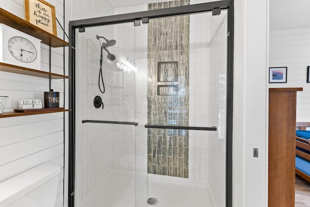 bathroom featuring wood-type flooring, toilet, and a shower with shower door