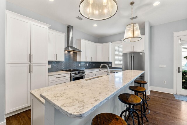 kitchen featuring wall chimney exhaust hood, premium appliances, a healthy amount of sunlight, and white cabinetry