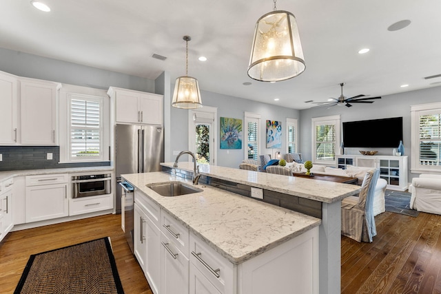 kitchen featuring decorative light fixtures, a kitchen island with sink, dark wood-type flooring, and sink