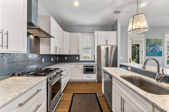 kitchen with white cabinetry, high end appliances, and wall chimney exhaust hood