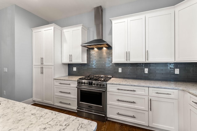 kitchen featuring tasteful backsplash, white cabinetry, high end stainless steel range, and wall chimney range hood