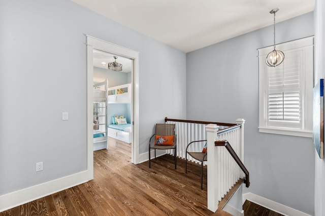 corridor with hardwood / wood-style flooring and an inviting chandelier