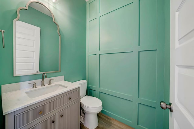 bathroom with wood-type flooring, vanity, and toilet