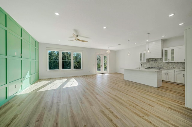 unfurnished living room with ceiling fan, light hardwood / wood-style flooring, and sink