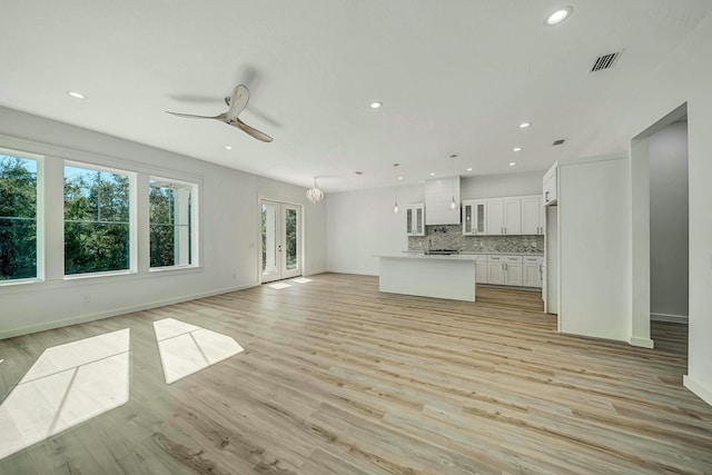 unfurnished living room featuring ceiling fan, french doors, and light hardwood / wood-style flooring