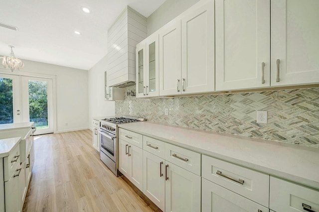 kitchen featuring white cabinets, light wood-type flooring, backsplash, and high end stainless steel range