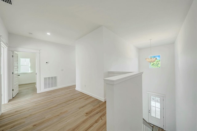 empty room featuring light hardwood / wood-style floors, a healthy amount of sunlight, and a notable chandelier