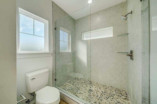 bathroom featuring tiled shower and toilet