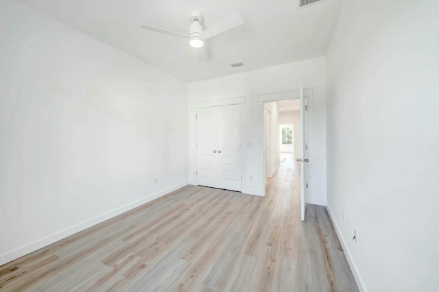 unfurnished bedroom with ceiling fan, light wood-type flooring, and a closet