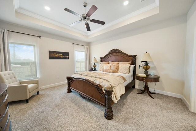 carpeted bedroom with a raised ceiling, ceiling fan, and ornamental molding