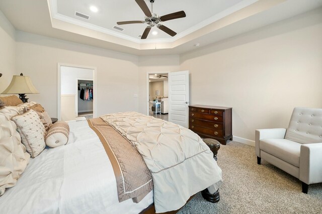 bedroom featuring a walk in closet, ceiling fan, and light carpet