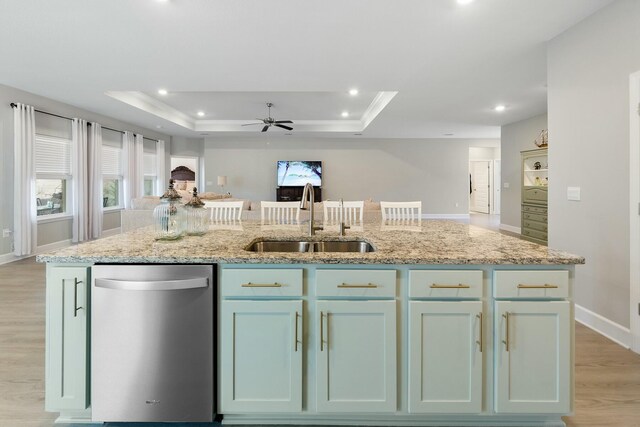 kitchen featuring dishwasher, sink, a tray ceiling, and an island with sink