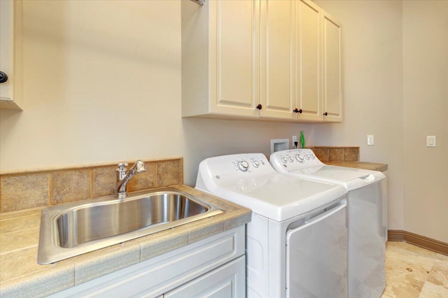 clothes washing area with cabinets, sink, and washer and dryer